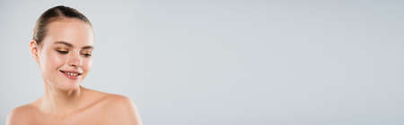 panoramic concept of happy young woman smiling and looking away isolated on grayの写真素材