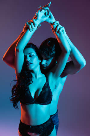 shirtless man touching hands of seductive woman in lingerie on purpleの写真素材
