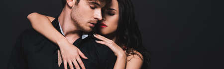 panoramic shot of sexy young woman hugging passionate boyfriend isolated on blackの写真素材
