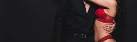 horizontal crop of passionate man hugging girl in red lingerie isolated on blackの写真素材