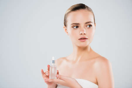 attractive young woman holding bottle with serum isolated on grayの写真素材