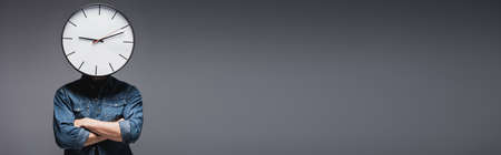 Panoramic shot of man with clock on head with crossed arms on gray background, concept of time...