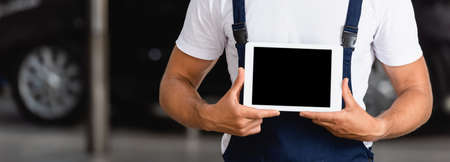 horizontal crop of mechanic in overalls holding digital tablet with blank screen in car service