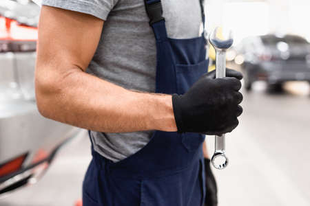 cropped view of mechanic in latex glove and uniform holding wrenchの写真素材