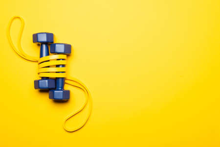 top view of blue dumbbells in resistance band on yellow backgroundの写真素材