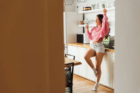 Selective focus of cheerful woman holding cup of coffee in kitchen at morningの写真素材