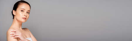 beautiful woman with perfect skin looking at camera isolated on gray, panoramic shotの写真素材