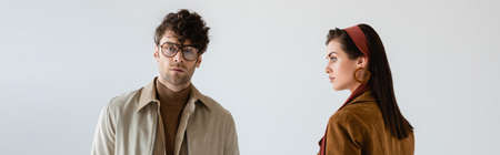 panoramic shot of young, fashionable couple in autumn clothes posing on grayの写真素材