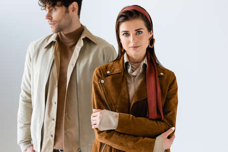 selective focus of stylish girl with crossed arms looking at camera near trendy, handsome man...