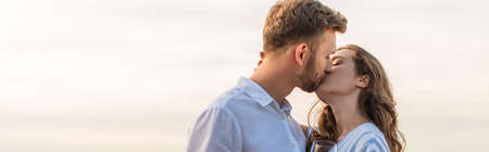 panoramic shot of bearded man kissing girlfriend outsideの写真素材