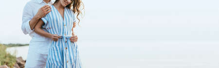 horizontal crop of man hugging happy woman touching dress