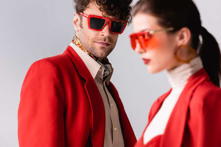 selective focus of stylish man looking at camera near trendy woman isolated on grayの写真素材