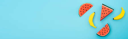top view of paper watermelon and bananas on blue background, panoramic shotの写真素材
