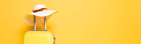 yellow travel bag with sun hat and sunglasses isolated on yellow, panoramic shotの写真素材