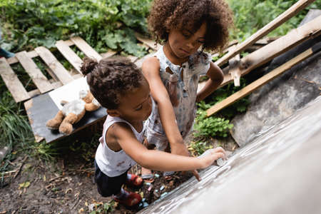 overhead view of poor african american kids writing on chalkboard outsideの写真素材