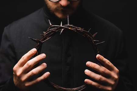 selective focus of priest holding wreath with spikes in hands isolated on blackの写真素材