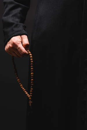 partial view of pastor holding rosary beads in hand isolated on blackの写真素材