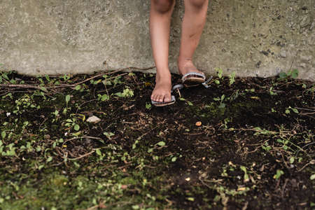 Cropped view of feet of poor african american child on ground near concrete wall outdoorsの写真素材