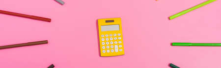 top view of calculator in frame of color felt-tip pens on pink, horizontal imageの写真素材