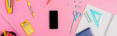 top view of smartphone with blank screen near school stationery on pink, horizontal conceptの写真素材