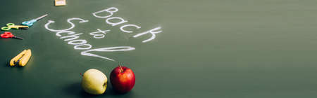 selective focus of ripe apples near back to school lettering and school supplies on green...