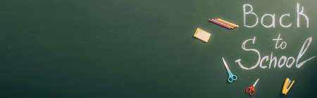 top view of back to school inscription near school stationery on green chalkboard, website header
