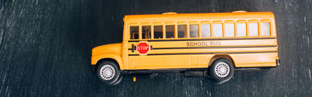 top view of yellow school bus model with stop sign on black chalkboard, horizontal image