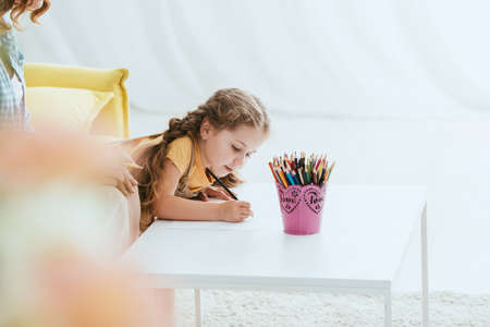 cropped view of babysitter near adorable child drawing with pencil, selective focusの写真素材