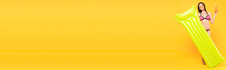 panoramic concept of happy girl in sunglasses holding cocktail and inflatable mattress on yellowの写真素材