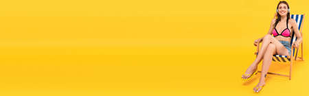 panoramic concept of happy girl in swimsuit and headphones sitting on deck chair on yellow