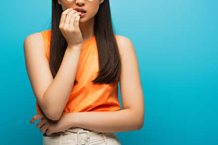 cropped view of worried woman touching mouth isolated on blue