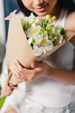 Cropped view of young woman holding bouquet of alstroemeria at homeの写真素材