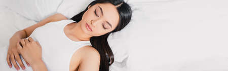 Panoramic shot of asian woman sleeping on white bedding at morningの写真素材