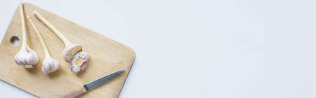 top view of garlic on wooden chopping board with knife on white background, panoramic shotの写真素材