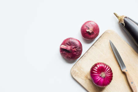 top view of purple whole vegetables, knife and wooden cutting board on white backgroundの写真素材
