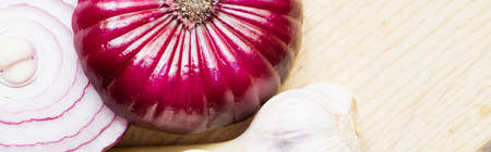 close up view of red onion and garlic on wooden cutting board, panoramic shotの写真素材