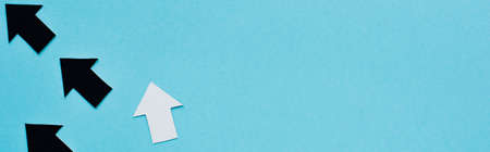 panoramic shot of black and white arrows on blue background, leadership concept