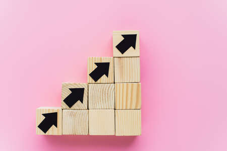 top view of wooden blocks with black arrows on pink background, business conceptの写真素材