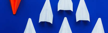 top view of white and red paper plans on blue background, leadership concept, panoramic shot