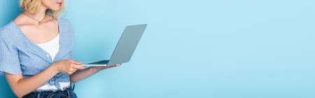 panoramic crop of young woman using laptop on blueの写真素材
