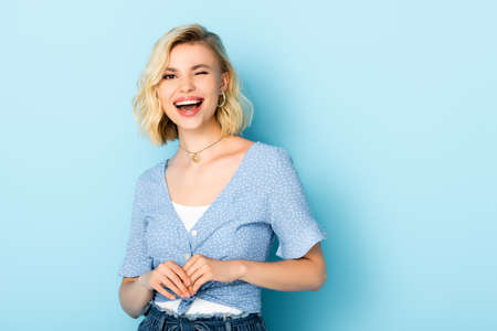 young woman looking at camera and winking eye on blue