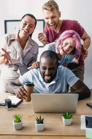 Selective focus of multiethnic business people using laptop together in office