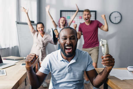 Selective focus of african american businessman showing yeah gesture with colleagues at background