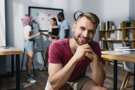 Selective focus of businessman looking at camera with coworkers at background in officeの写真素材