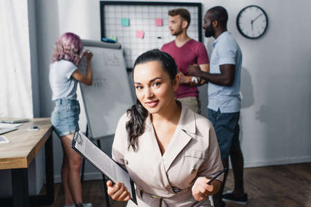 Selective focus of businesswoman holding pen and clipboard in office
