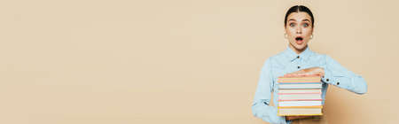 surprised student in denim shirt with books on beige, panoramic shotの写真素材