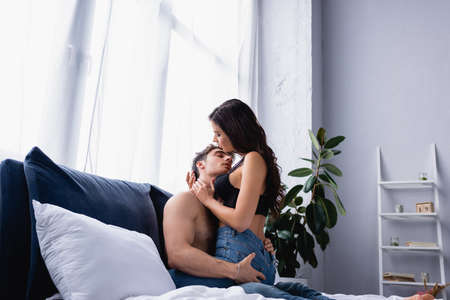 seductive woman hugging shirtless man in bedroomの写真素材