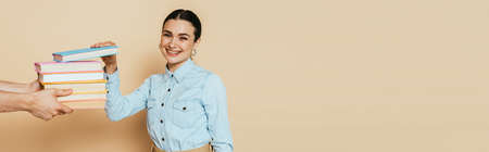 student in denim shirt taking books on beige, panoramic shotの写真素材