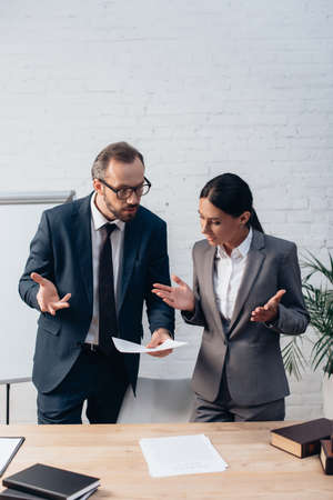 lawyers in formal wear gesturing while talking and looking at insurance documentの写真素材