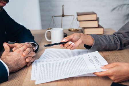 cropped view of lawyer giving pen to businessman near insurance policy contract in officeの写真素材